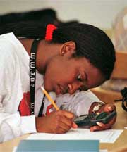A photo of an undergraduate writing on paper her calculator's calculation. 